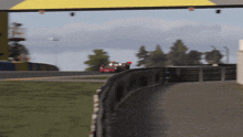 a race car is driving down a track with a yellow roof in the background