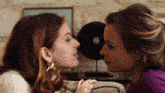 two women are looking at each other with one wearing a ring on her finger