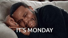a man is crying while laying on a couch with the words " it 's monday " written above him