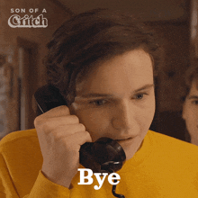 a man in a yellow shirt is talking on a telephone with the word bye written below him