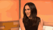 a woman in a black dress is sitting in a chair on a television show .