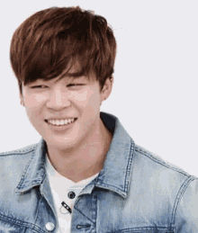 a young man wearing a denim jacket is smiling .