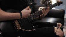 a man is playing a black guitar with a gold trim