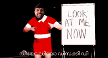 a man in a red dress stands in front of a white board that says " look at me now "
