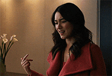 a woman in a red coat is pointing her finger at something