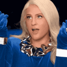 a blonde woman wearing blue gloves and a necklace