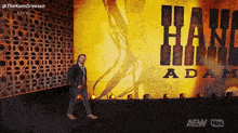 a man stands in front of a wall that says hang adam on it