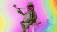 kermit the frog is playing a banjo while sitting on a table .