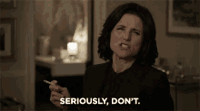 a woman is smoking a cigarette and saying `` seriously , don 't . ''