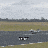 a fighter jet is taking off from a runway and the words ok jet are above it