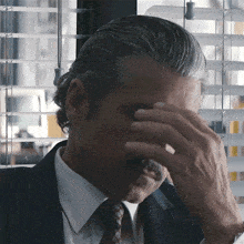 a man in a suit and tie is covering his eyes with his hand