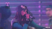 a woman is singing into a microphone in front of a screen that says 13 anos