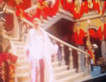a woman in a white dress is walking down stairs