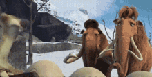 a group of mammoths are standing in the snow .