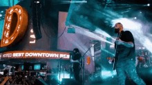 a man playing a guitar in front of a sign that says " voted best downtown res "