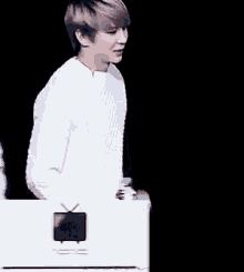 a man in a white sweater is standing next to another man in a black background .