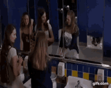 a woman is standing in front of a mirror in a public bathroom .