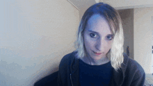 a woman with blonde hair is wearing a black hoodie