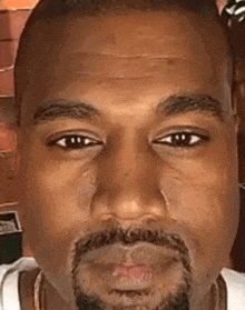 a close up of kanye west 's face with a beard and a tear coming out of his eye .