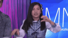 a girl in a plaid dress is making a funny face in front of a sign that says mn .