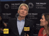 a man in a suit is being interviewed by a woman in front of a wall that says the paley center for media