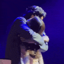 a blurry picture of two people hugging each other in front of a blue background