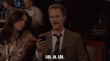 a man in a suit and tie is looking at his phone and says lol jk lol