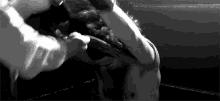 a black and white photo of two men boxing in a boxing ring .