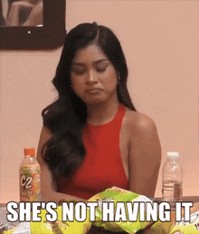 a woman is sitting at a table with a bag of chips and a bottle of c2 cheese