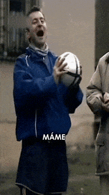 a man in a blue jacket is holding a soccer ball with the word mame written below him