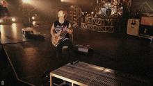 a man playing a guitar wearing a band shirt