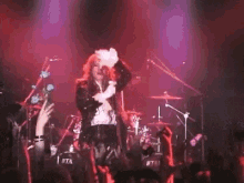 a man is singing into a microphone on a stage in front of a crowd of people .