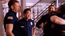 a group of firefighters are hugging and laughing in a hallway