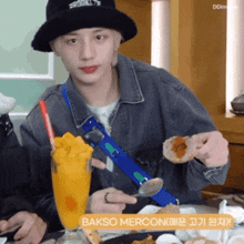 a man sitting at a table with a spoon in his hand and a glass of bakso mercon behind him