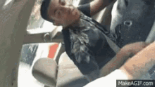 a man is laying in the back seat of a car being held by another person .