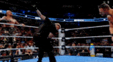 a referee is standing in a wrestling ring with two wrestlers