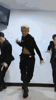 a group of men are dancing in a room with a tv in the background .