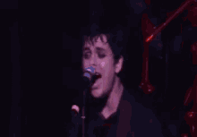 a close up of a man singing into a microphone with his eyes closed .
