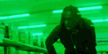 a man in a black jacket is standing next to a railing in a green room .