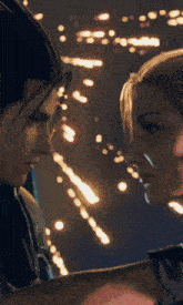 a man and a woman are looking into each other 's eyes with fireworks in the background