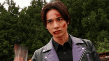 a man wearing a black shirt and a purple leather jacket has a red spot on his face
