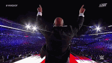 a man in a suit is giving the middle finger in front of a crowd at a wrestling event