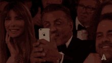 a man in a tuxedo is taking a picture of a woman with an apple phone