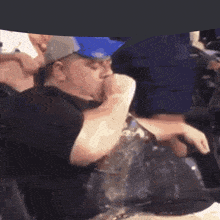 a man in a baseball cap is drinking from a cup