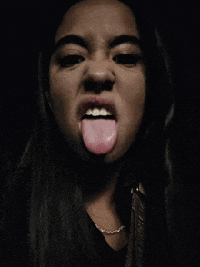 a woman sticking her tongue out and wearing a chain around her neck