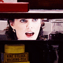 a woman behind a shelf with a box of nine o'clock washing tea