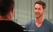 a man in a blue shirt is talking to another man in a kitchen and says wish me luck