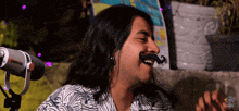 a man with a fake mustache is smiling in front of a microphone that says shure