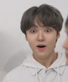 a young man with gray hair is making a surprised face .