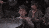 a group of young boys are standing around a pot of water .